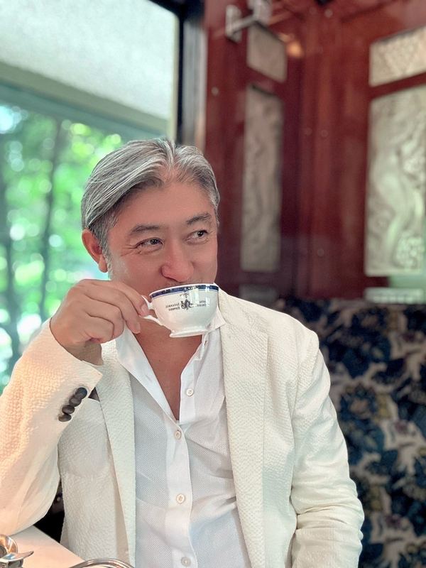 白いジャケットでコーヒーを味わう西田理一郎