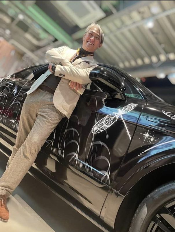 ショールームで黒い車にもたれる西田理一郎