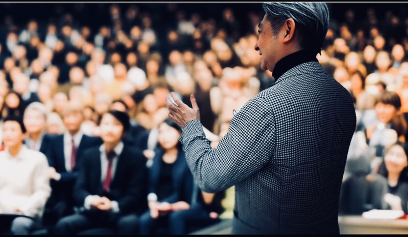 大勢の聴衆を前に講演する西田理一郎