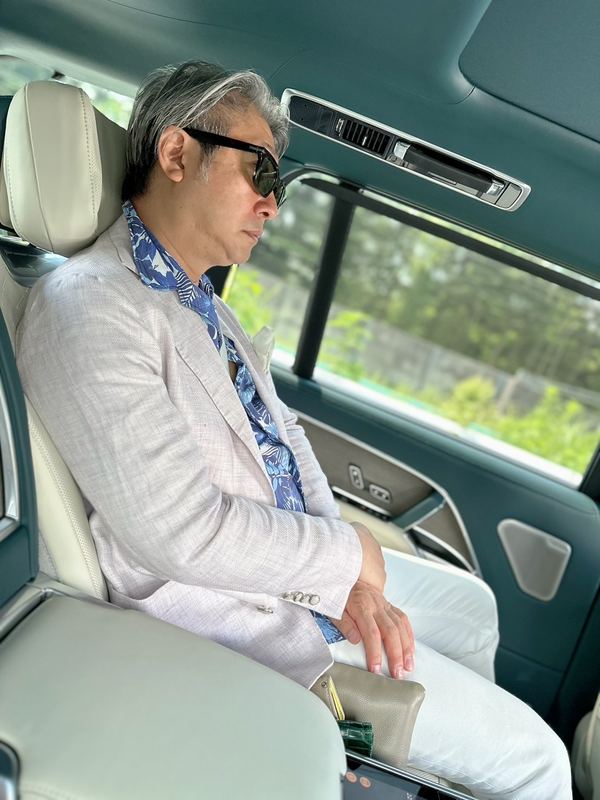 高級車の後部座席に座る西田理一郎