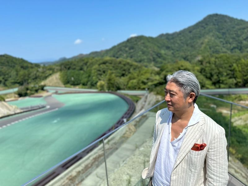 山と湖を望むテラスに立つ西田理一郎