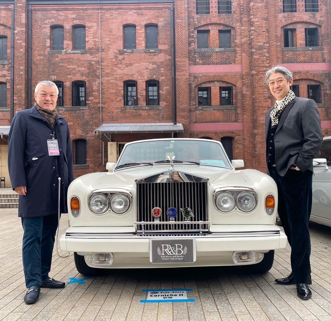 白いロールス・ロイス コーニッシュIIを挟んで並ぶ西田理一郎とクラブの仲間